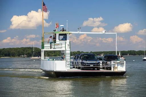 Passenger ferry carrying cars across the water under a blue sky