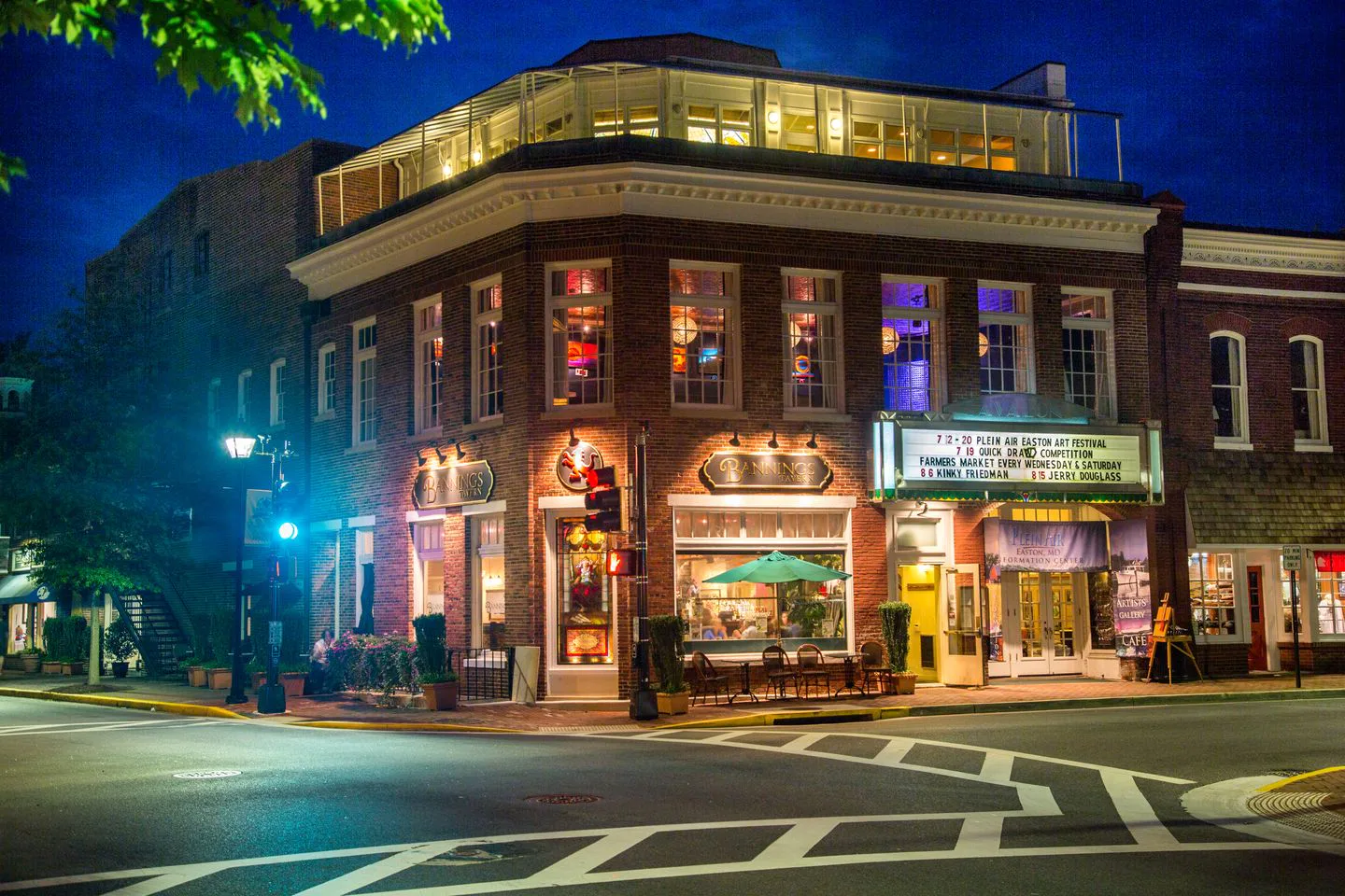 Historic brick storefronts lit up at dusk along a quiet Easton street