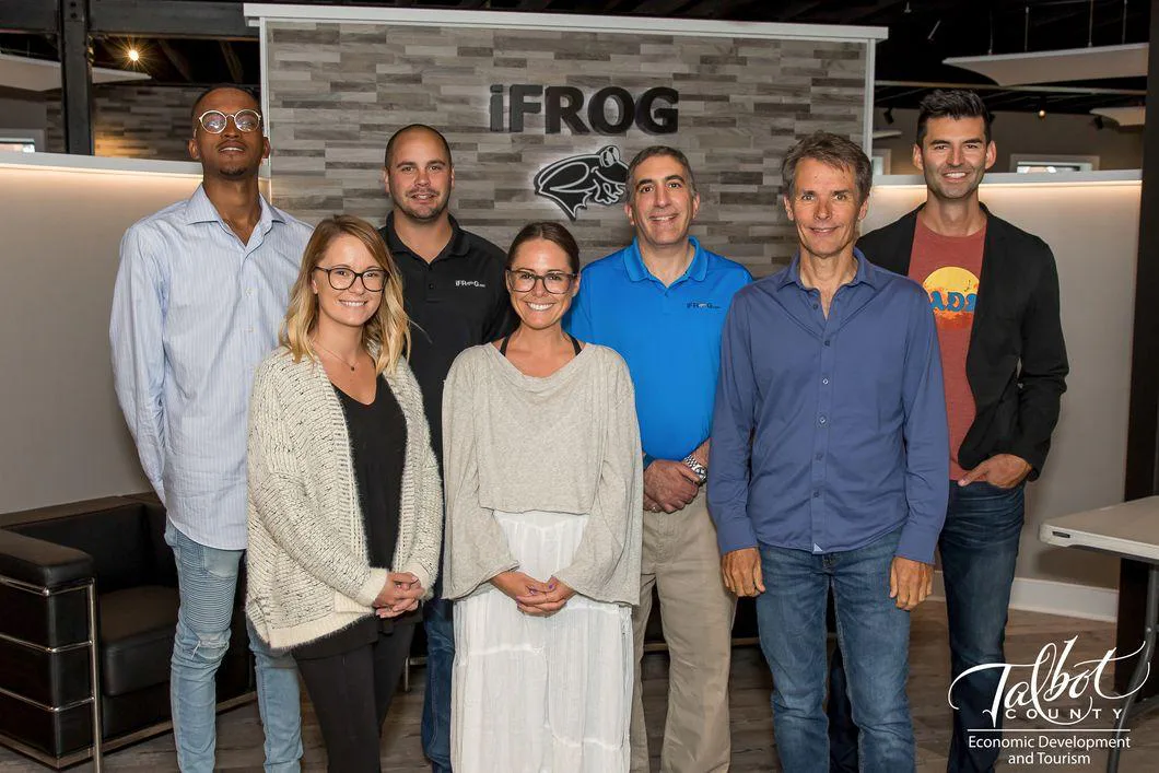 Seven people posing in front of an IFROG logo display