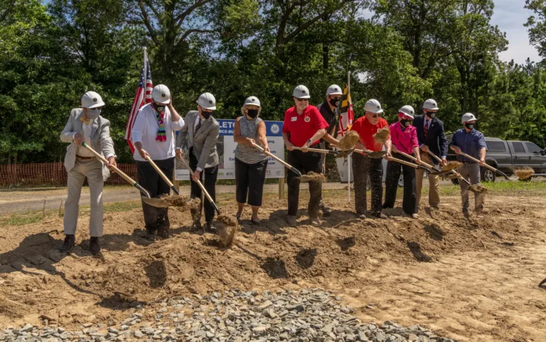 Group in hard hats holding shovels at a groundbreaking ceremony