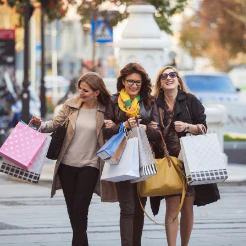 Three women walking a sidewalk carrying shopping bags