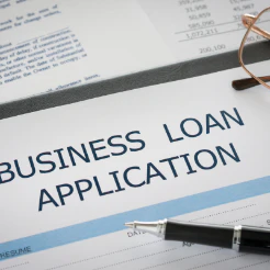 Pen and eyeglasses resting on a printed Business Loan Application form