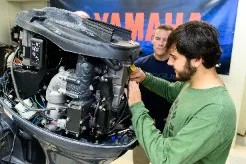 Two men working on a Yamaha outboard motor