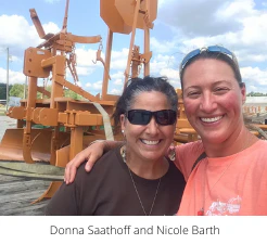 Donna Saathoff and Nicole Barth smiling in front of orange equipment
