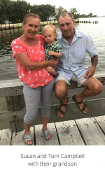 Susan and Tom Campbell with their grandson on a dock by the water