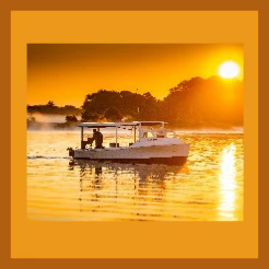 Small boat with a canopy on calm water at golden sunset