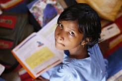 Young girl looking up while holding an open book