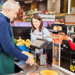 Shopper placing bananas on a checkout counter while a cashier smiles