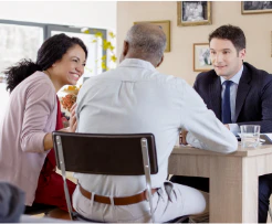 Woman leaning over a restaurant table to speak with two seated men