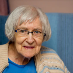 Smiling older woman with glasses against a blue background