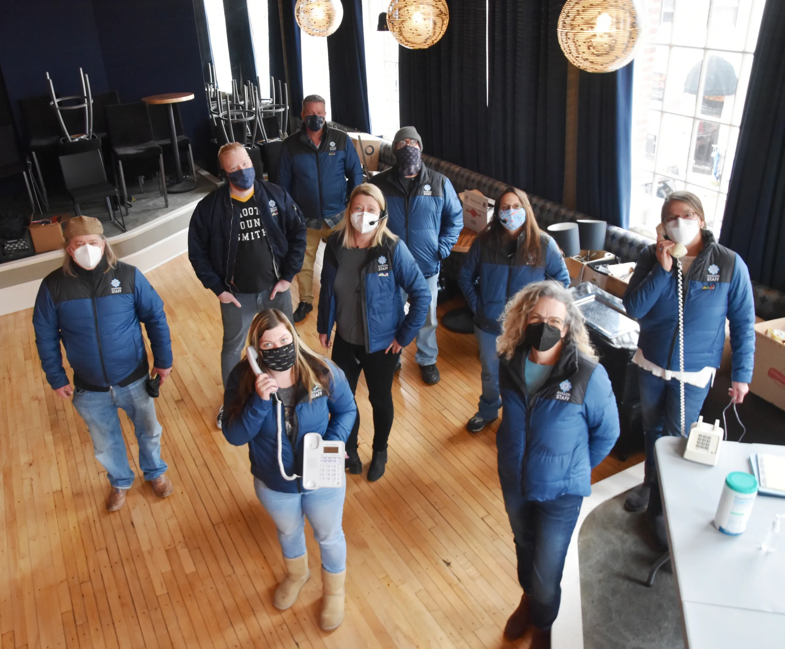 Group in matching blue jackets and face masks standing in a large event room