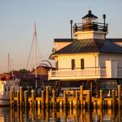 Small lighthouse on pilings at the water edge at sunset