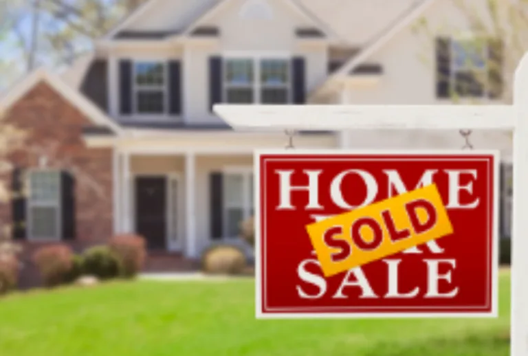 Red for sale sign reading HOME FOR SALE with a SOLD sticker in front of a brick house