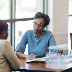 Woman in a blue sweater meeting with a colleague across a table