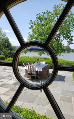 Round window view of a patio table and chairs overlooking the water