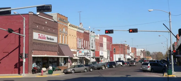 Small-town main street with brick storefronts, traffic lights and parked cars