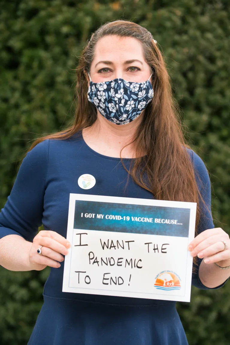 Woman in a face mask holding a sign that says I want the pandemic to end