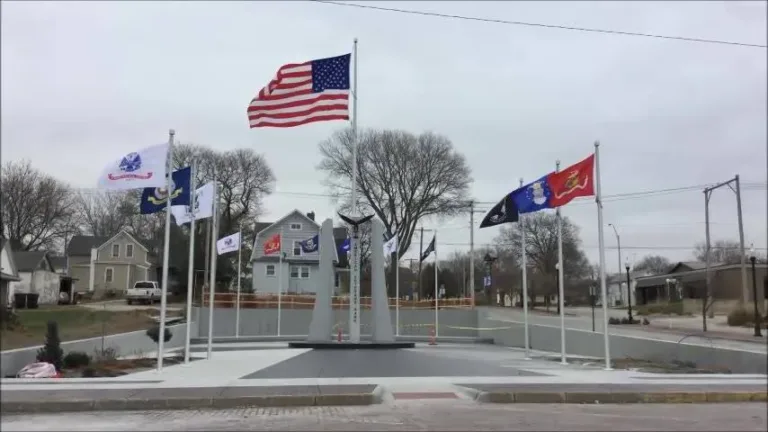 Memorial plaza with flagpoles flying the American flag and several military flags