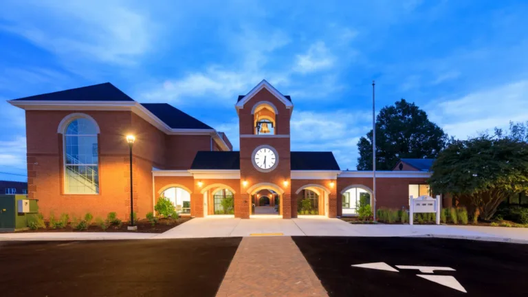 Brick building with a clock tower and lit entrance at dusk