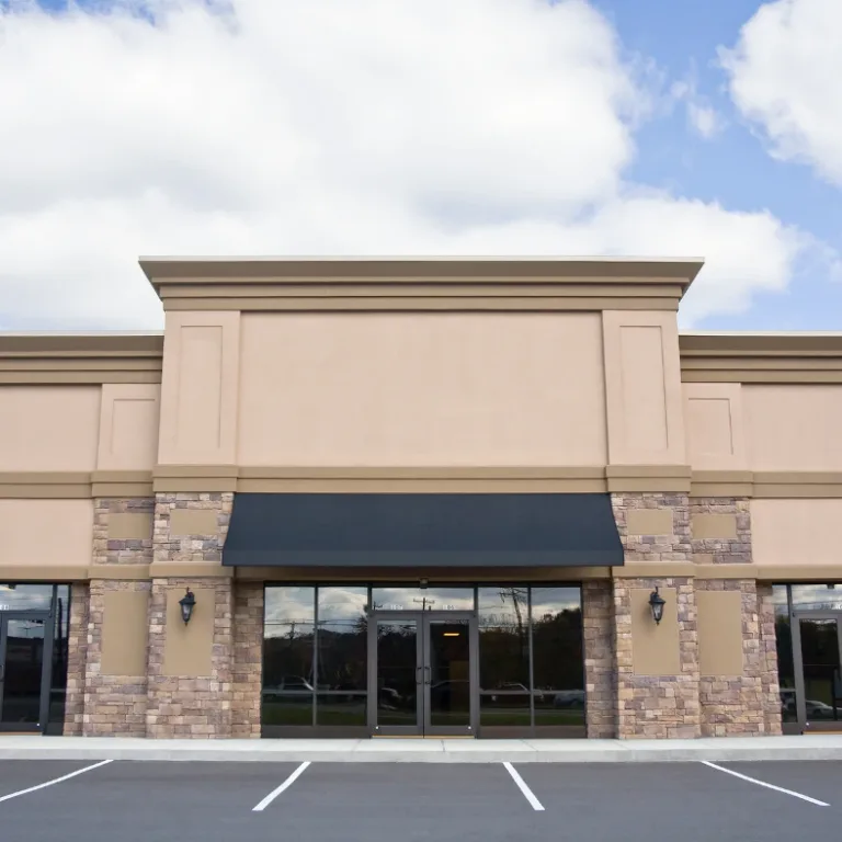 Empty tan retail building with glass storefront and black awning