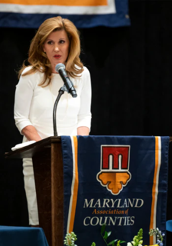Woman speaking at a podium beside a Maryland Association of Counties banner