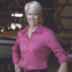 Smiling woman with short white hair in a bright pink shirt