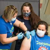 Health worker giving a COVID-19 vaccination shot to a woman at a clinic
