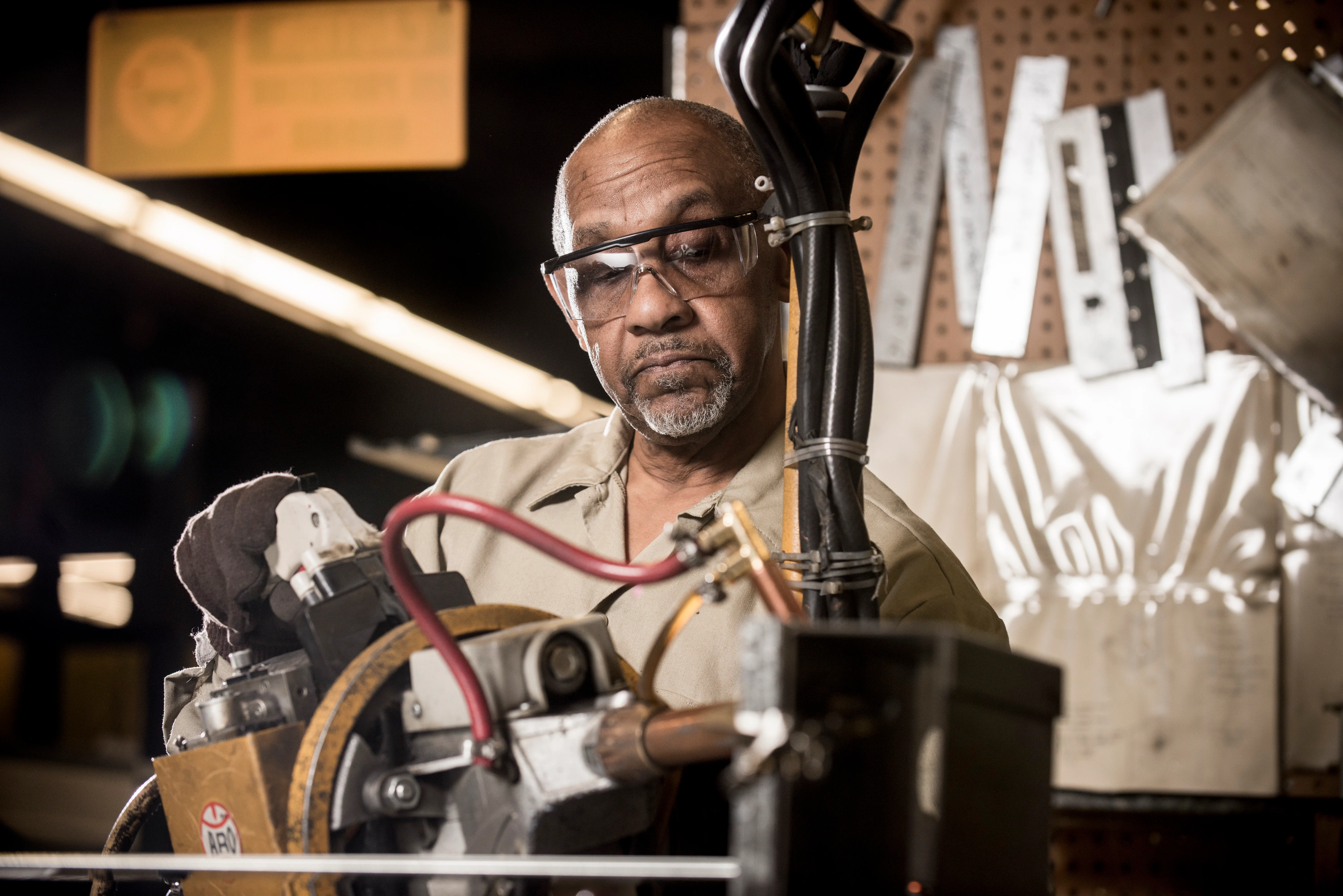 Man in safety glasses operating welding equipment with hoses