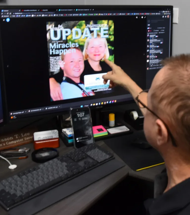 Man at a computer viewing a screen showing a magazine cover, UPDATE Miracles Happen
