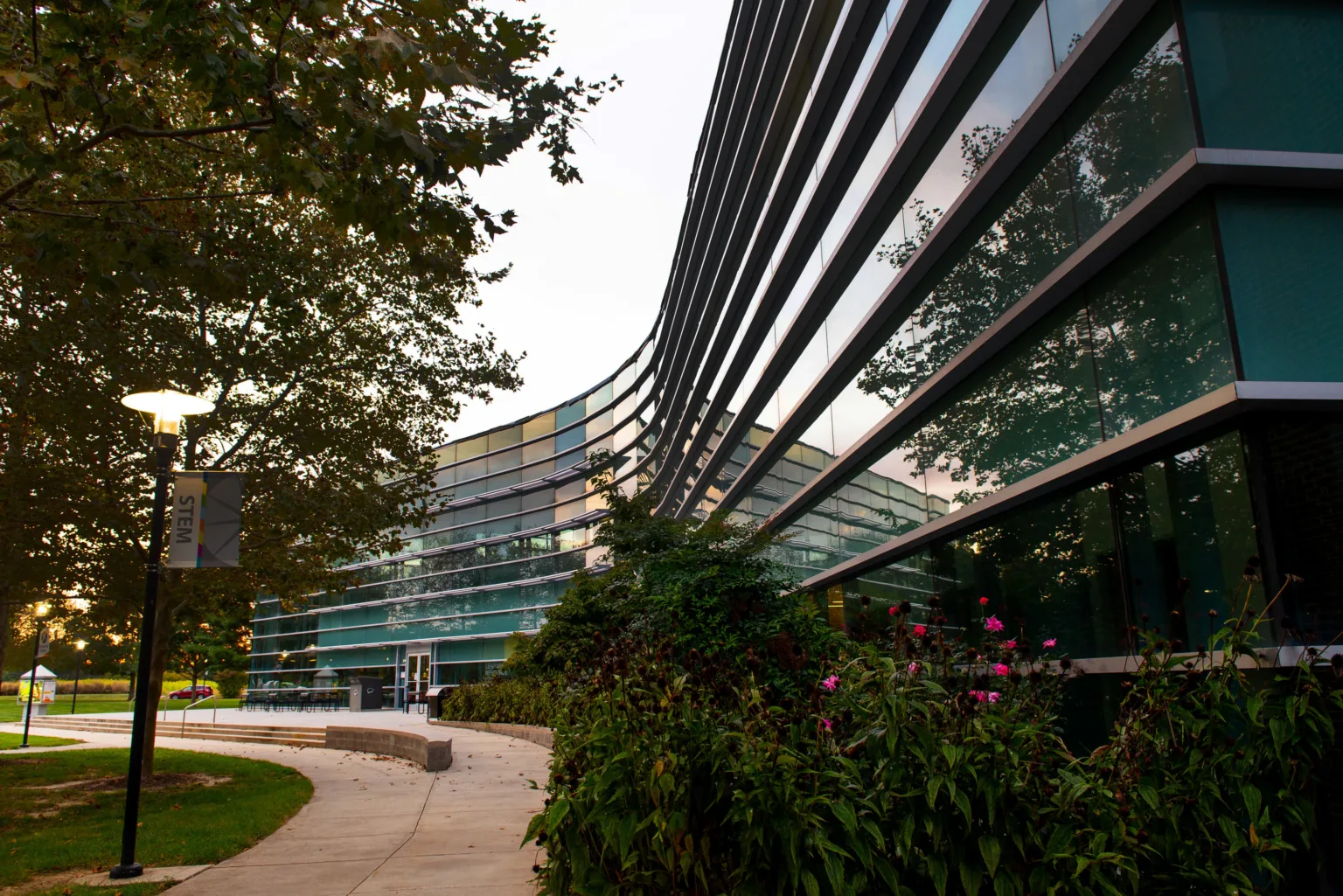 Curved glass building with trees and a walkway