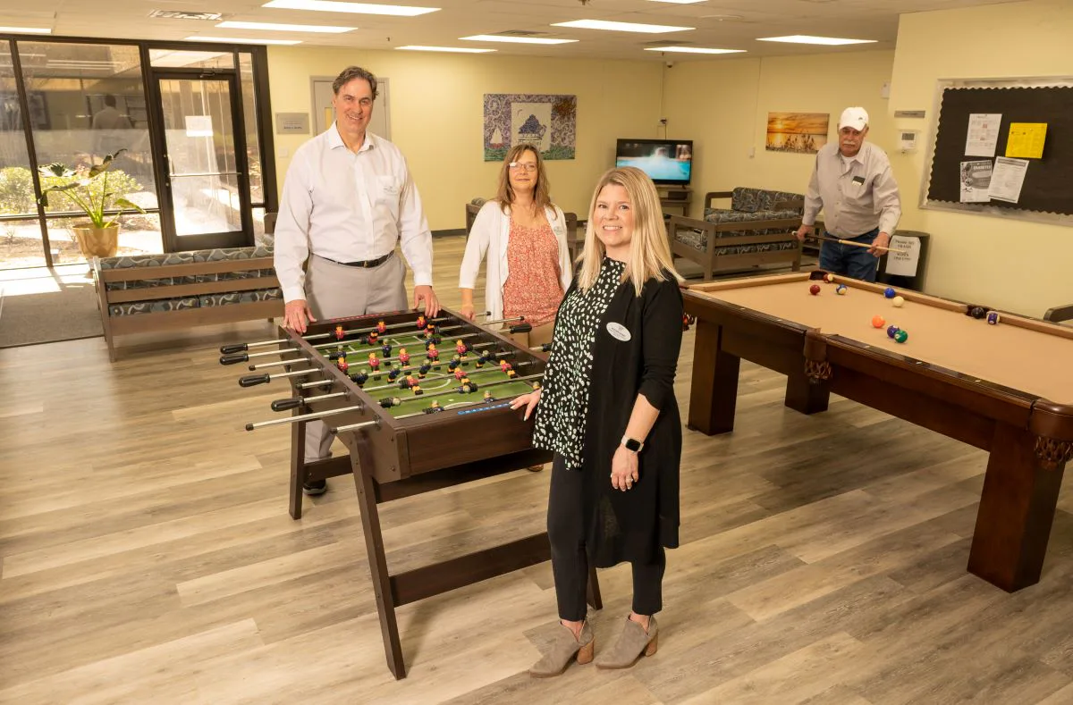 Staff members posing in an office game room with foosball and pool table