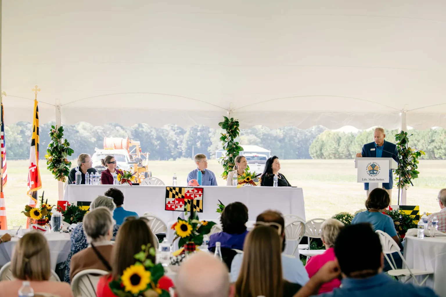 Outdoor reception under a tent with speakers at a head table