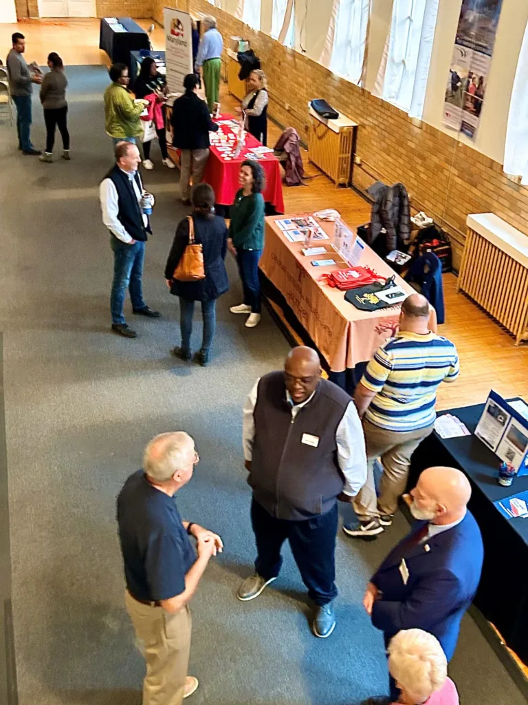 Attendees browsing a resource fair with tables and displays in a hall