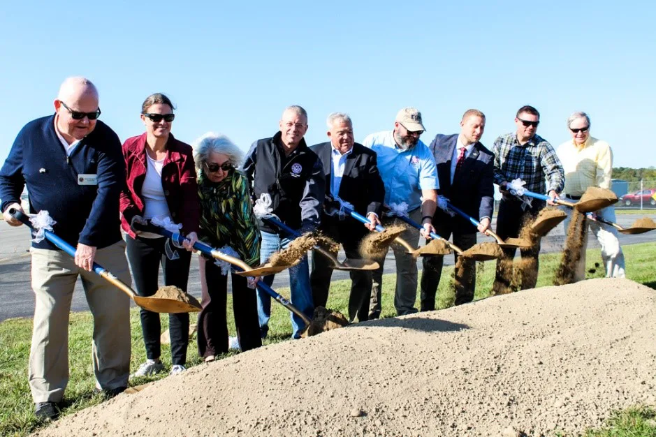 Group of officials holding shovels at an outdoor airport groundbreaking