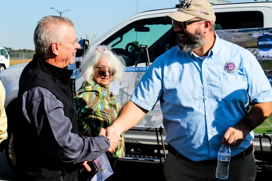 Man in cap shaking hands with an older woman beside a pickup truck