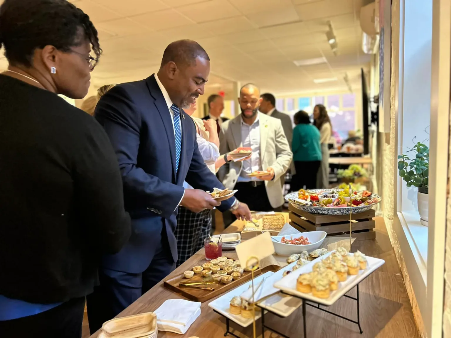 Man in suit at a catering table with food plates at a reception