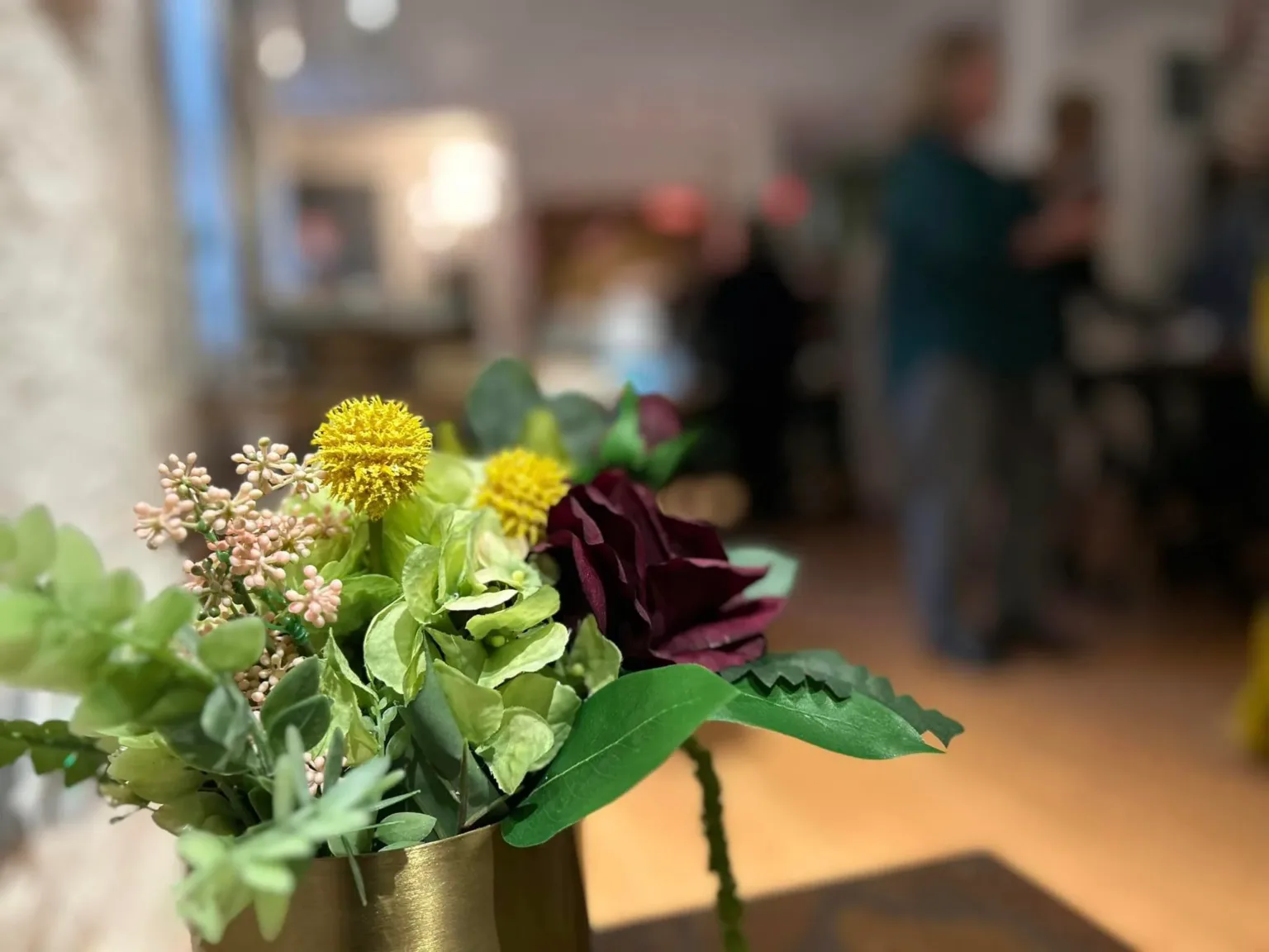 Floral arrangement of yellow, white, and burgundy flowers at an event