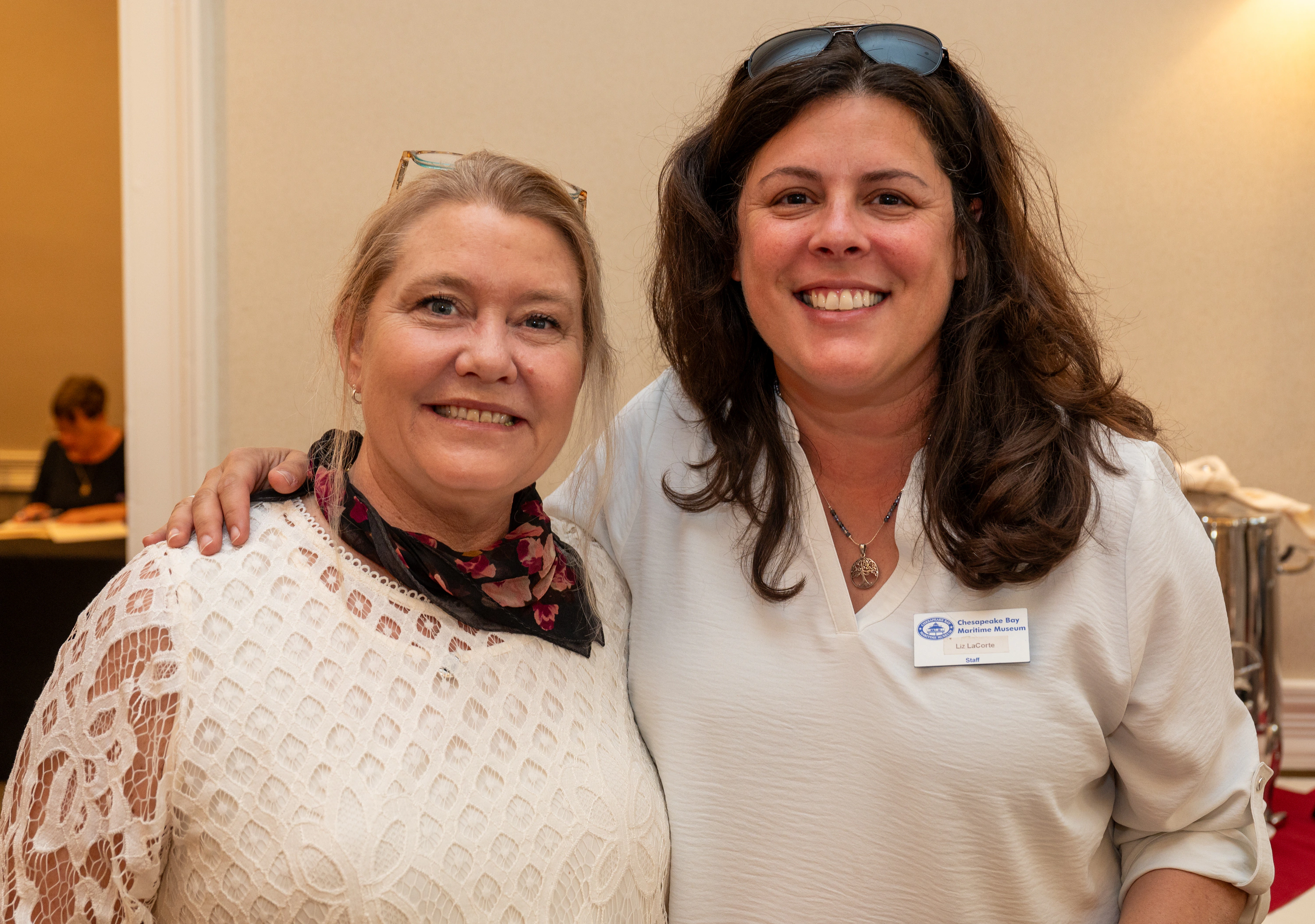 Two women smiling together, one wearing a name badge
