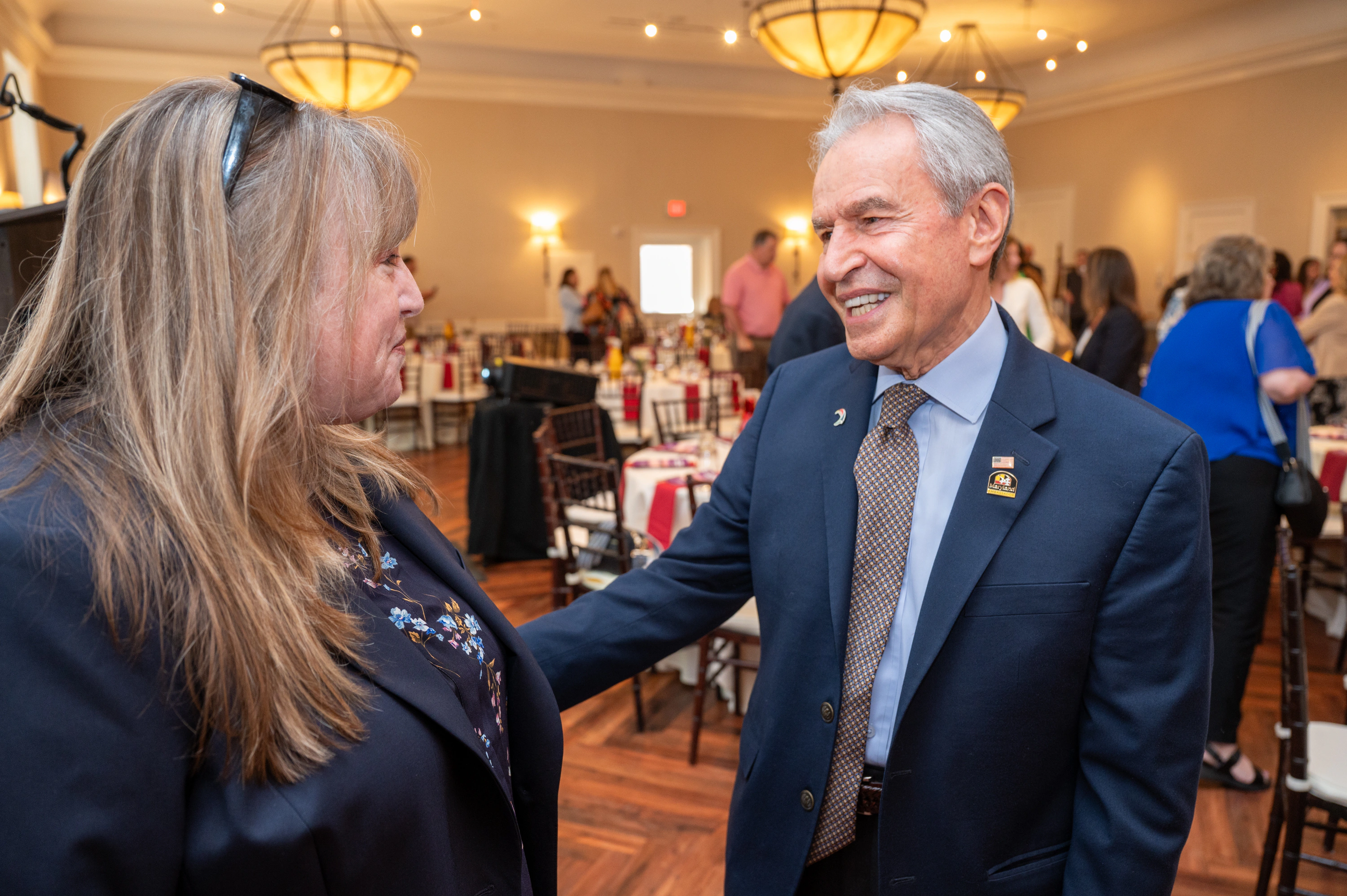 Woman talking with a smiling man in a blazer at a banquet event