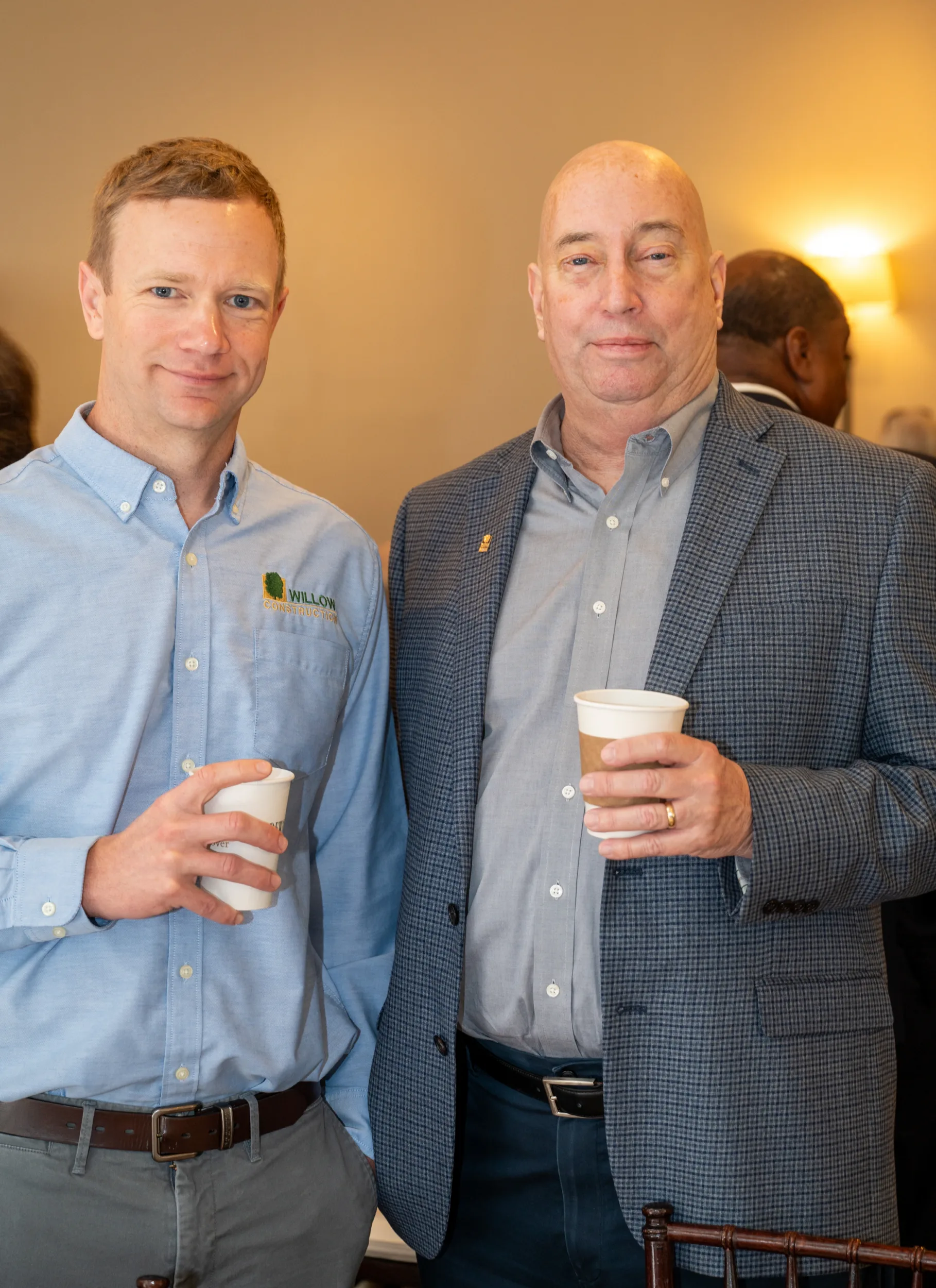 Three men holding coffee cups posing indoors at an event