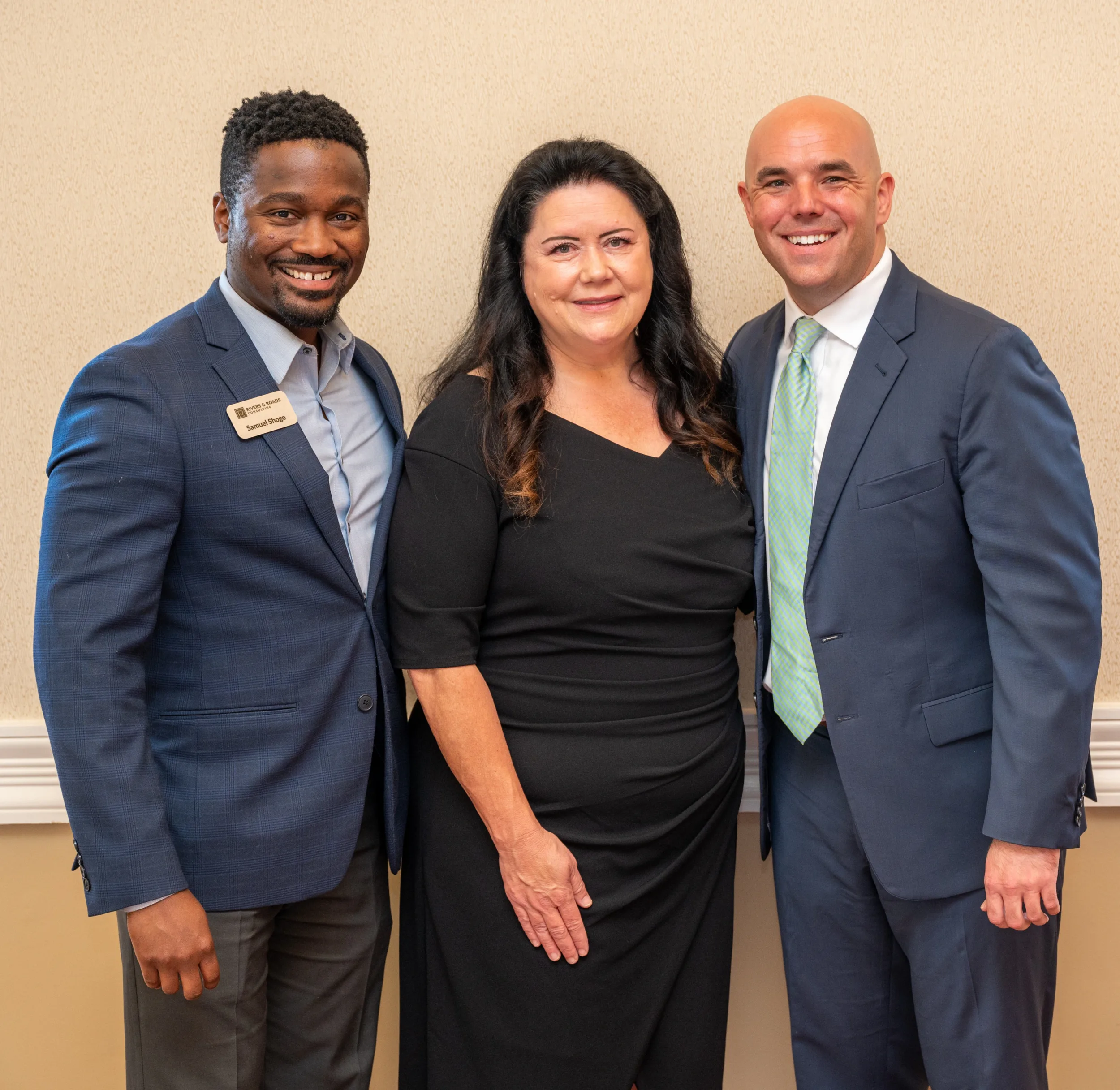 Man, woman, and man posing together in an event room