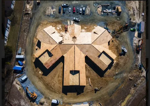 Aerial view of a large building under construction with wood framing and parking lot