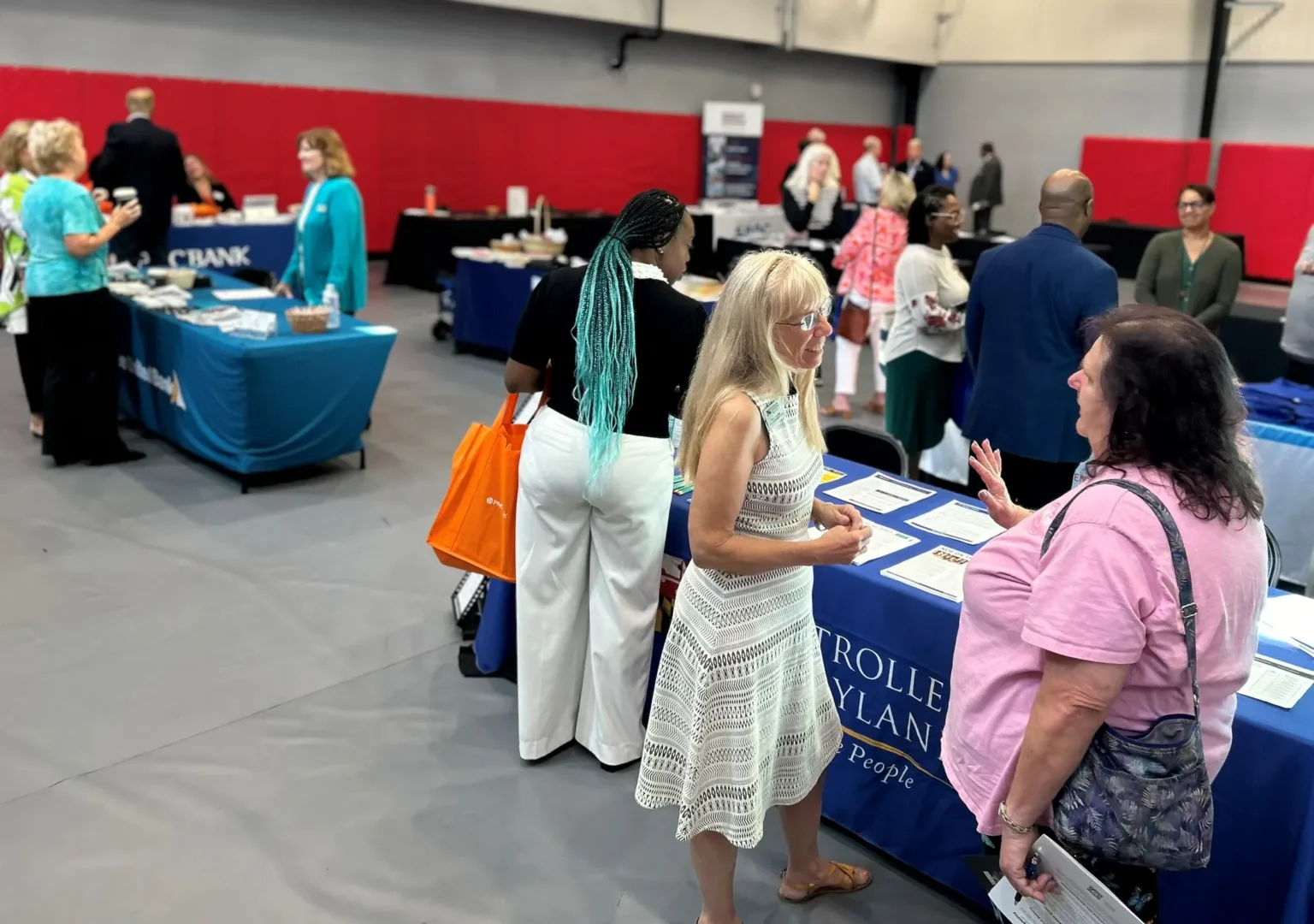 Attendees browsing exhibitor tables in a conference hall