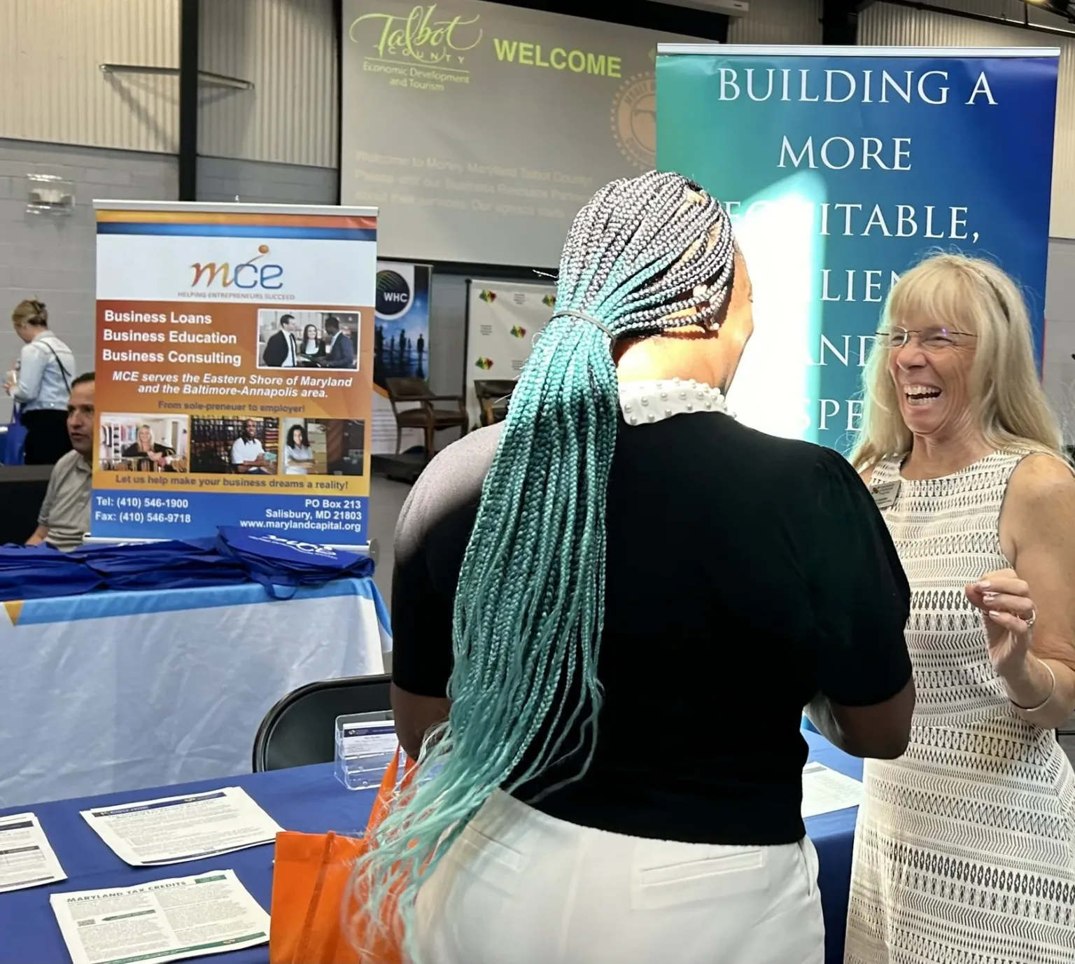 Woman talking with an exhibitor at an MCE booth in a conference hall