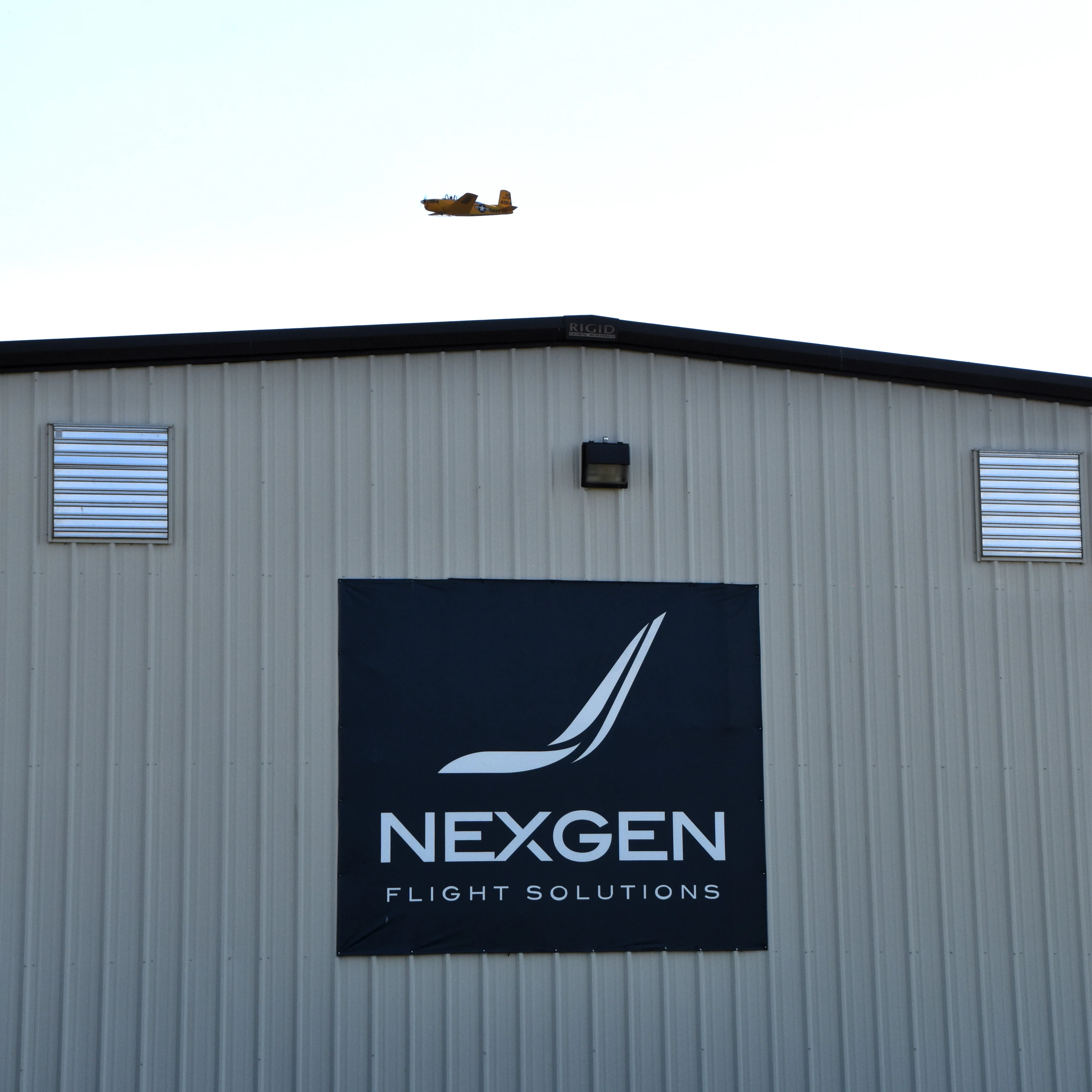 NEXGEN Flight Solutions sign on a metal hangar building