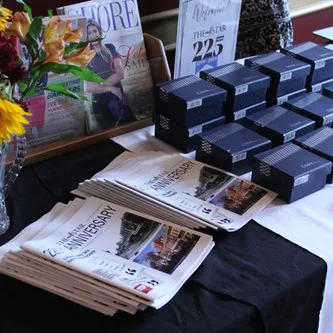Table with gift boxes and Star Democrat anniversary newspapers and flowers