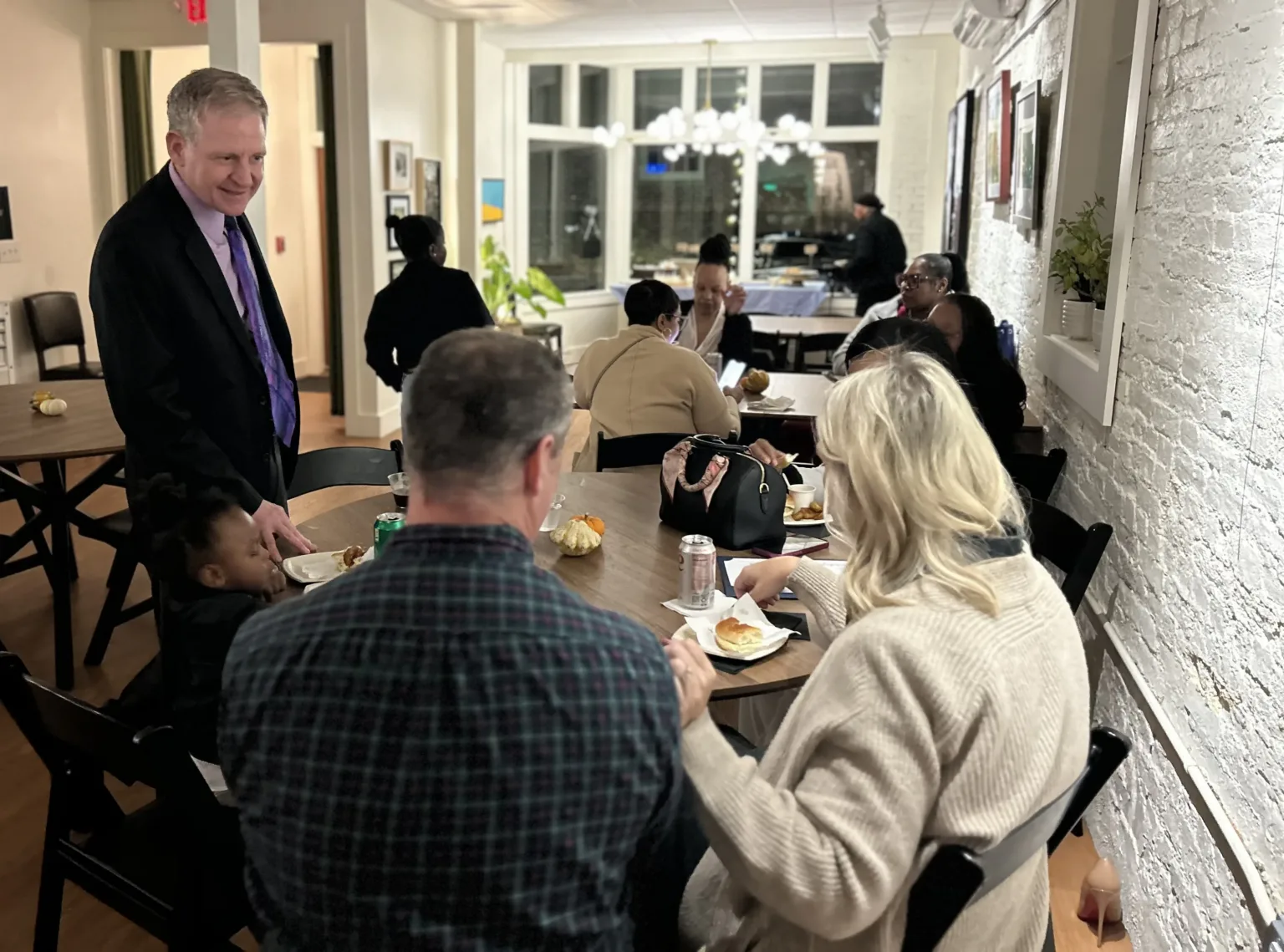 Man in suit serving guests seated at tables in a restaurant