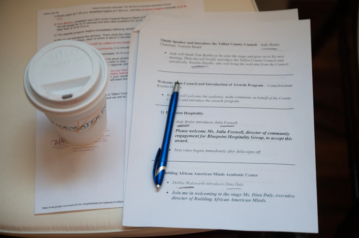 Printed agenda pages with a blue pen beside a paper coffee cup