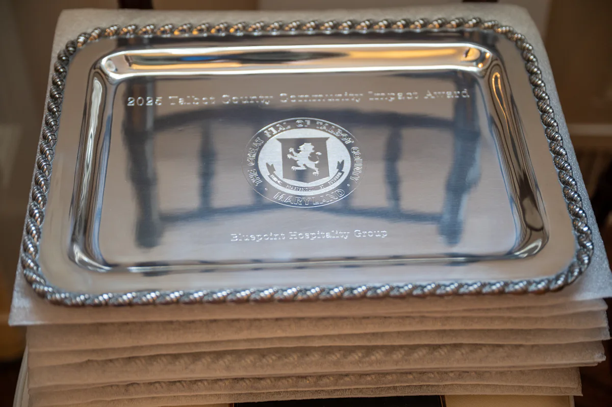Silver engraved serving tray with a central crest rests on a stack of boxes