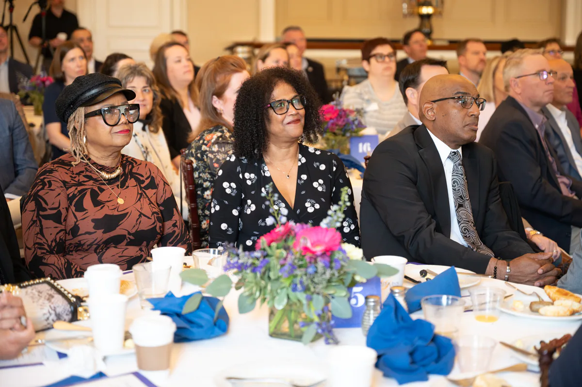 Woman in black floral dress sits at a banquet table decorated with flowers